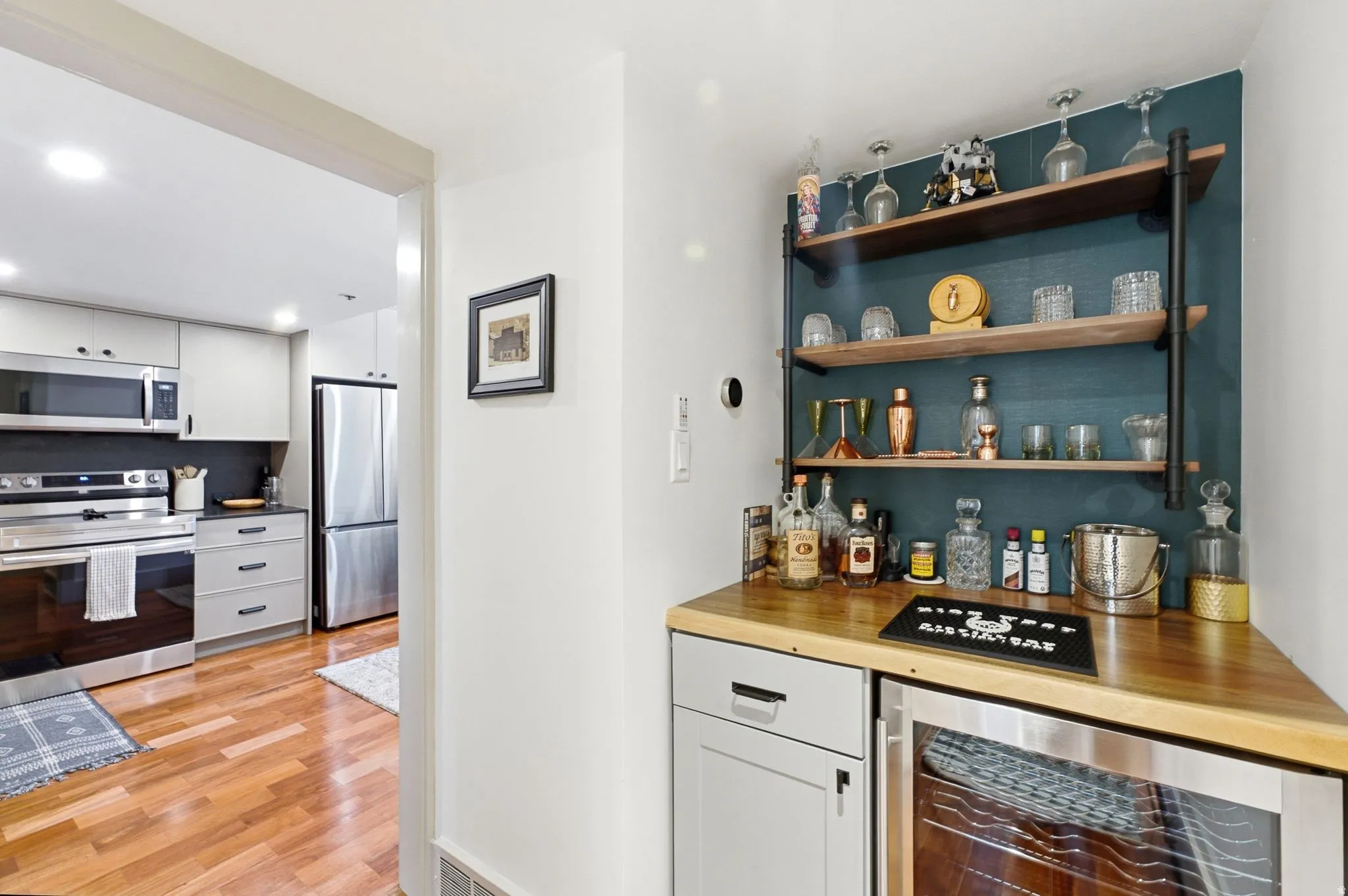 Custom built-in bar with wood-finish countertop, open shelving, and integrated beverage cooler