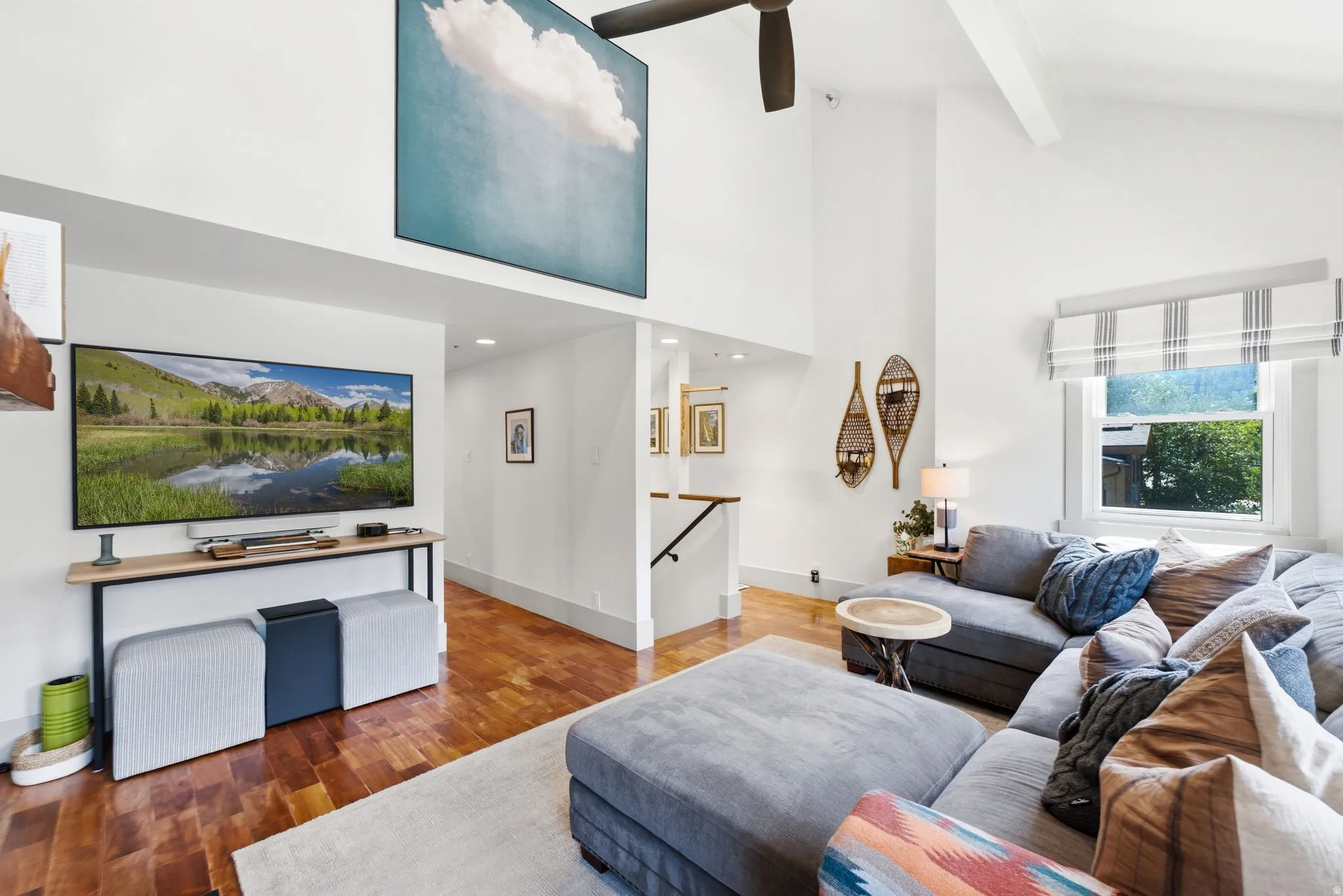 Vaulted ceilings with exposed beams, wood-finish flooring, recessed lighting, and a prominent window