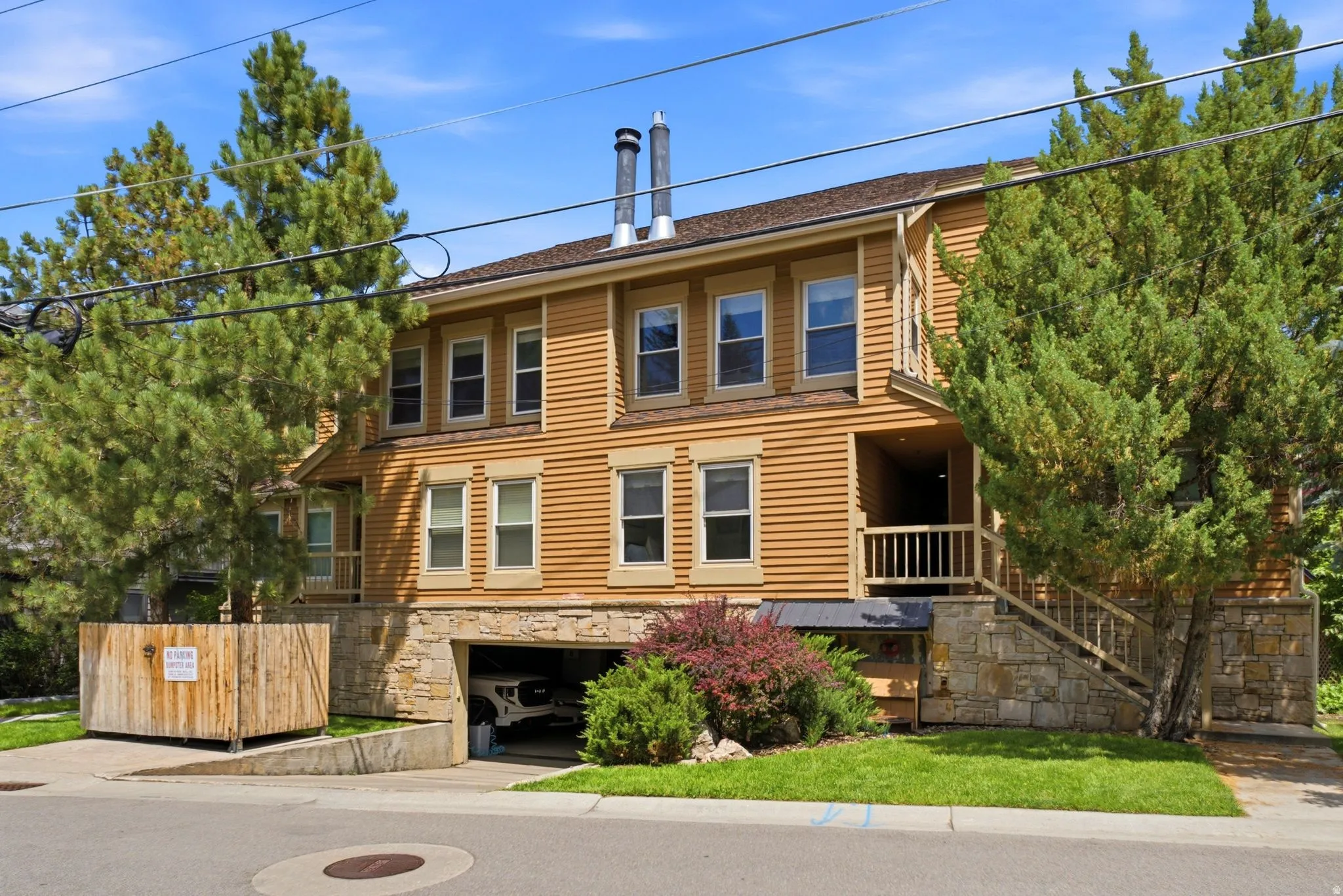 Multi-level property featuring a wood-sided exterior, stone foundation accents, and an integrated garage