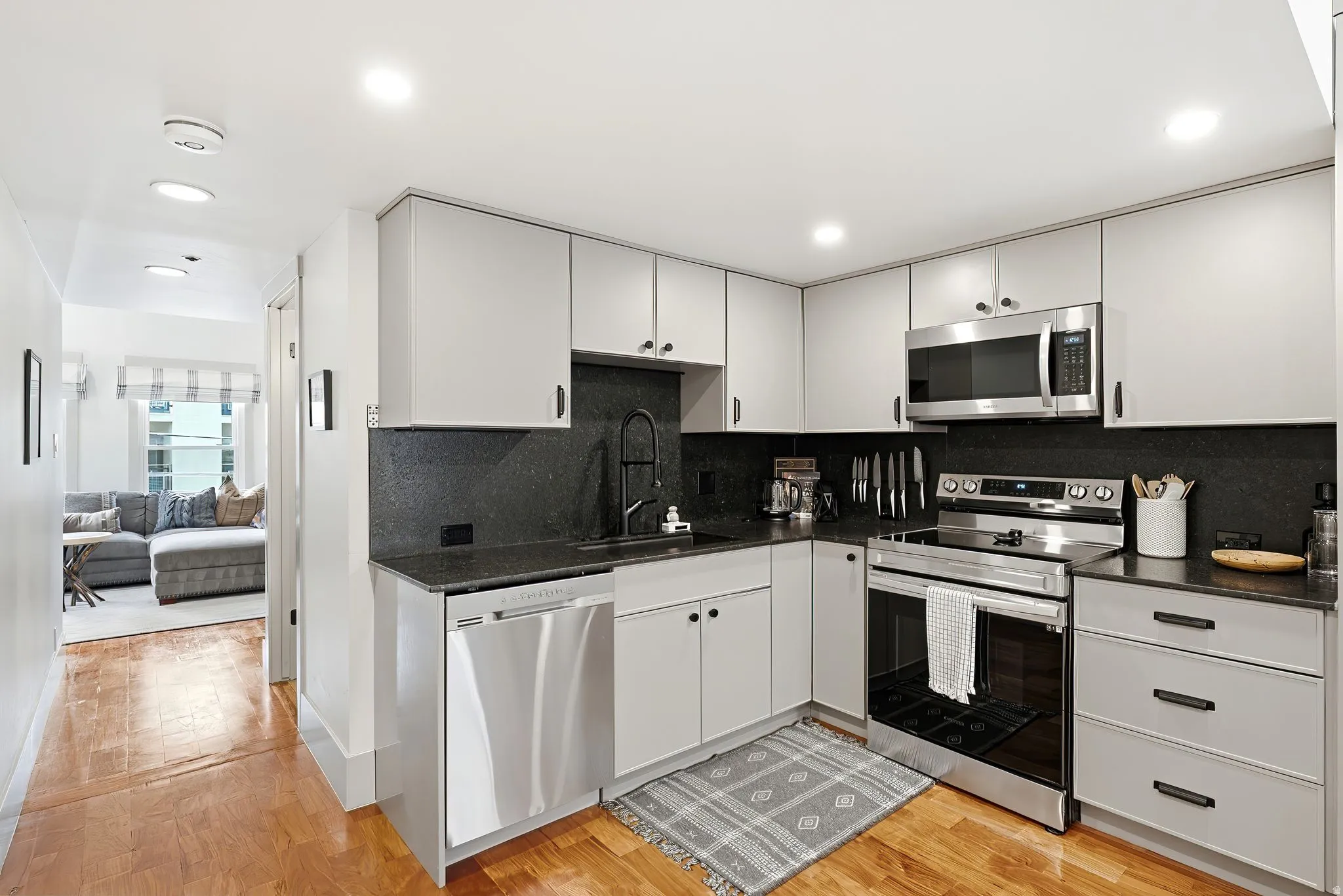 Kitchen featuring light-toned cabinetry, dark countertops, and stainless steel appliances including a range, microwave, and dishwasher