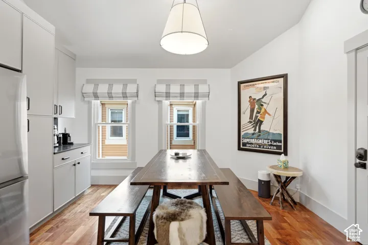 Recessed panel cabinetry with dark hardware, dark countertops, and wood-finish flooring