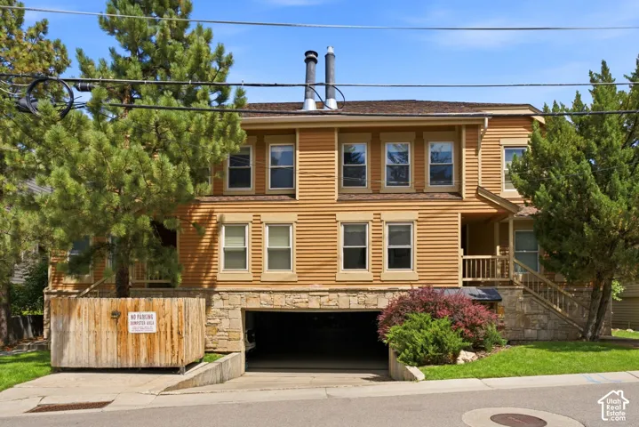 Two-story exterior with horizontal siding, stone foundation, covered entry, front porch with wood railing, and an integrated garage