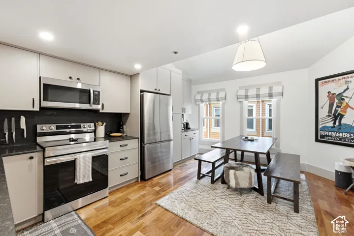 Kitchen featuring stainless steel appliances, light-toned cabinetry, and dark countertops