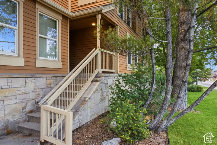 Stone veneer foundation with steps and a porch featuring a wood railing