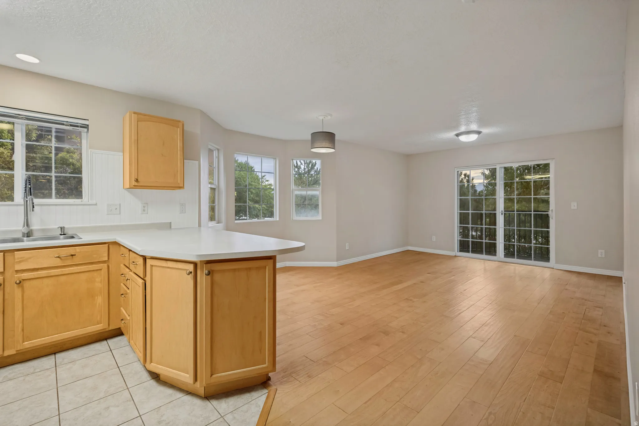 Kitchen with light wood cabinetry, white countertops, and a tile backsplash