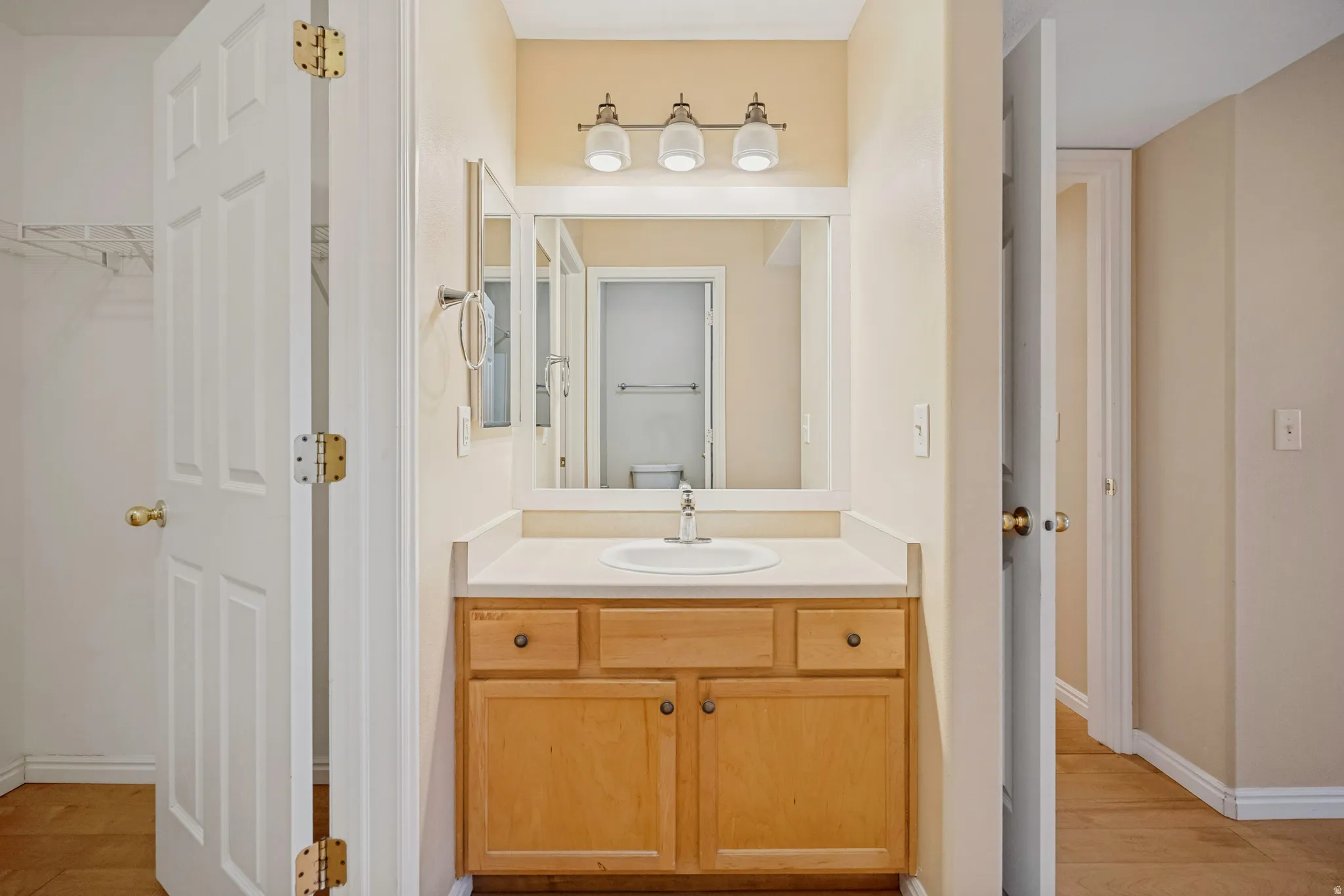 Single vanity with wood-finish cabinetry, a white countertop, and an undermount sink