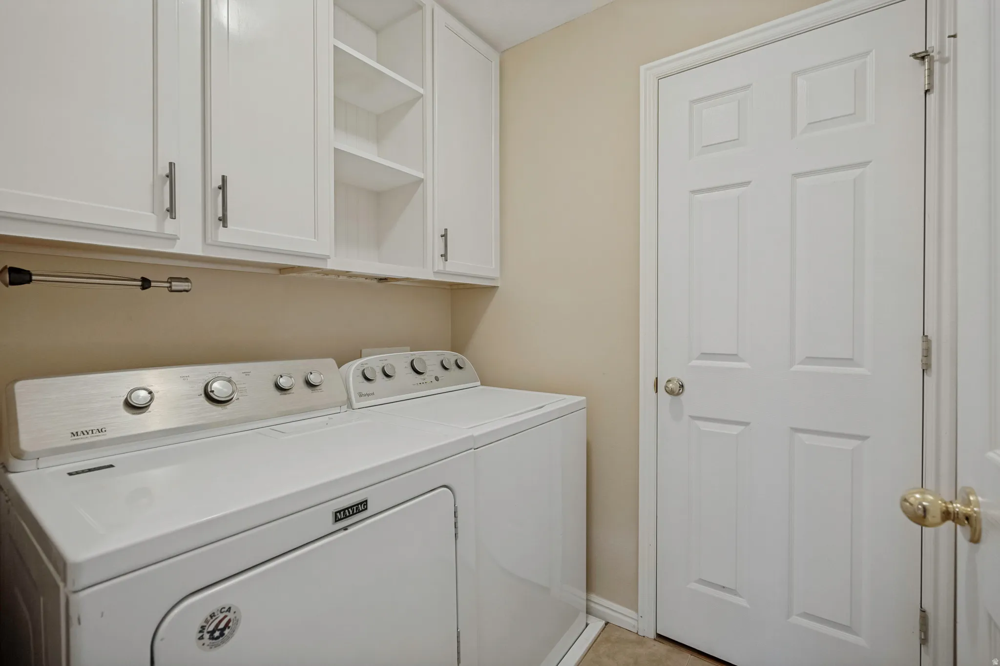 White cabinetry with brushed nickel hardware, open shelving, and a panel door