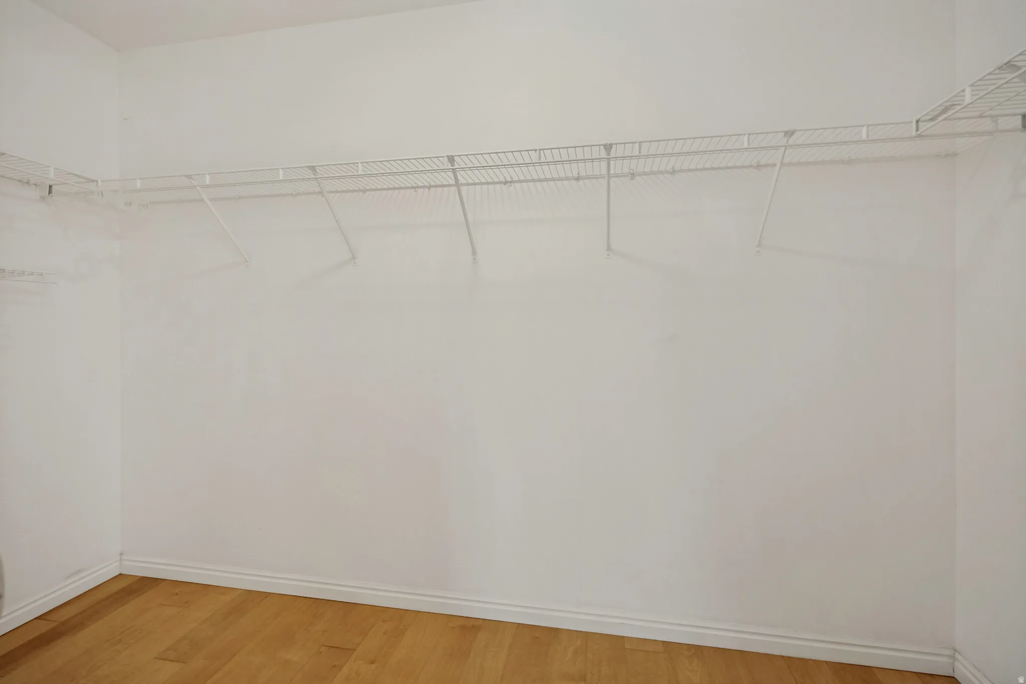 White wire shelving system, light wood-finish flooring, and white wall paint