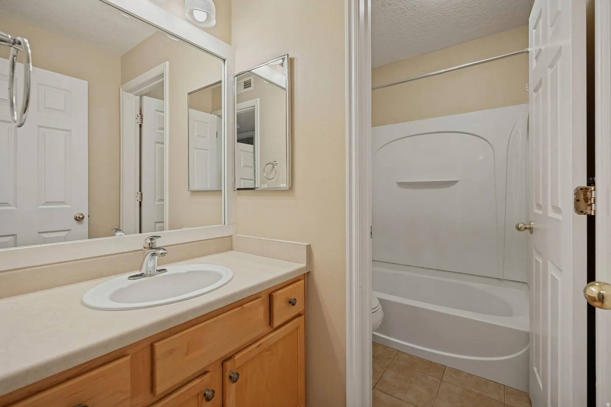 Bathroom vanity with a light-toned countertop, undermount sink, and wood-finish cabinetry