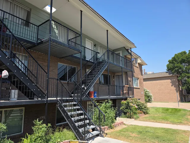 Brick exterior with a light-colored siding accent, multiple balconies with metal railings, and exterior metal staircases