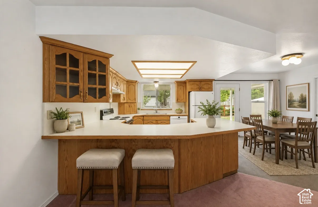 Kitchen with wood-finish cabinetry, white countertops, and a built-in breakfast bar