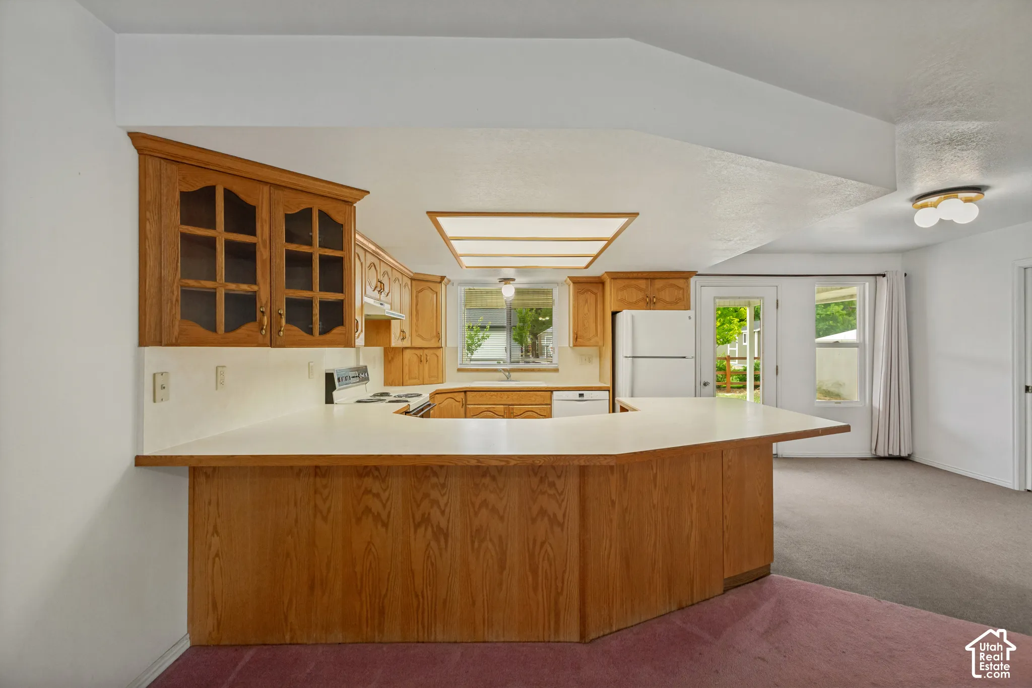 Wood-finish cabinetry with glass-front uppers, a U-shaped counter, and a built-in range