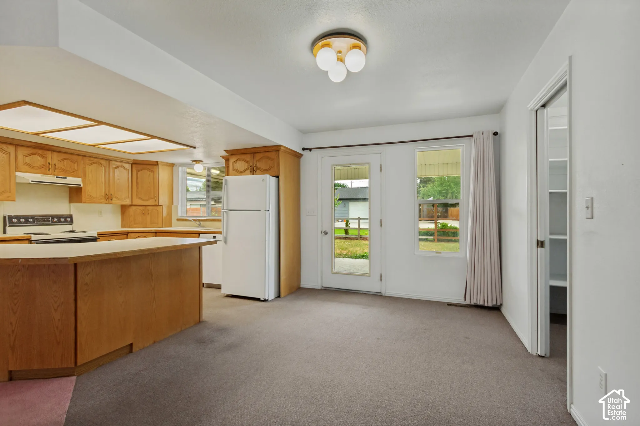 Kitchen with wood cabinetry and white appliances and dedicated semi formal dining area with pantry.