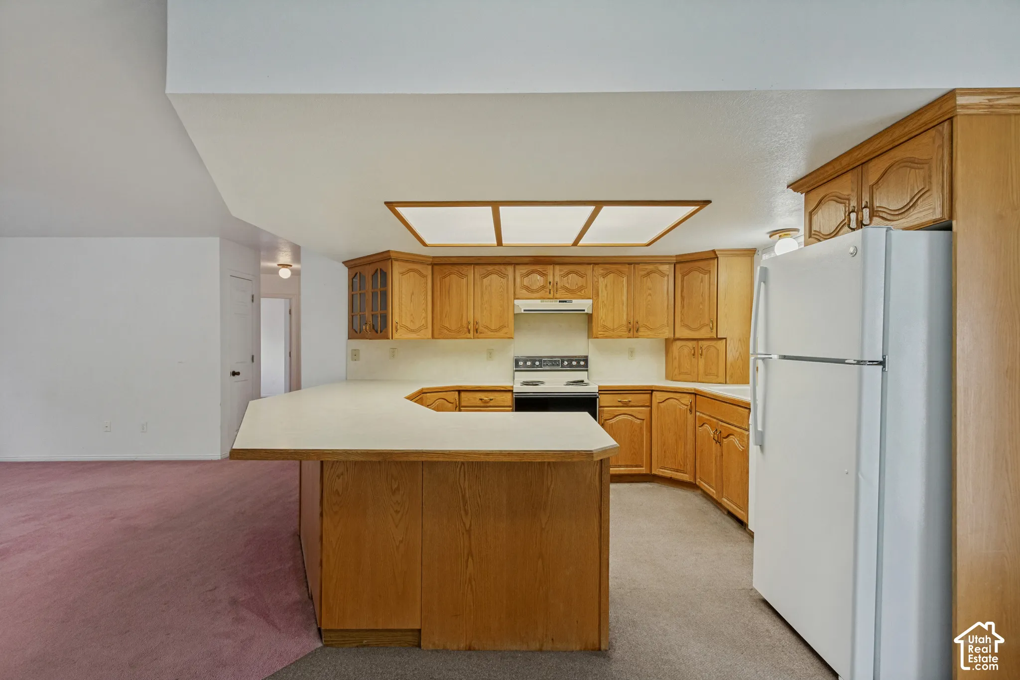 Kitchen featuring wood-finish cabinetry, white countertops, built-in range, and a breakfast bar