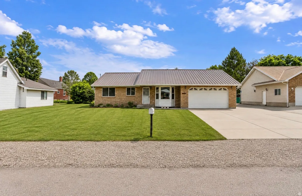 Brick exterior with a metal roof, attached two-car garage, and a concrete driveway