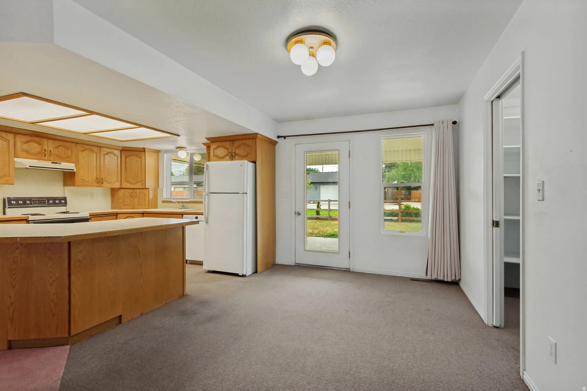Kitchen with wood cabinetry and white appliances and dedicated semi formal dining area with pantry.