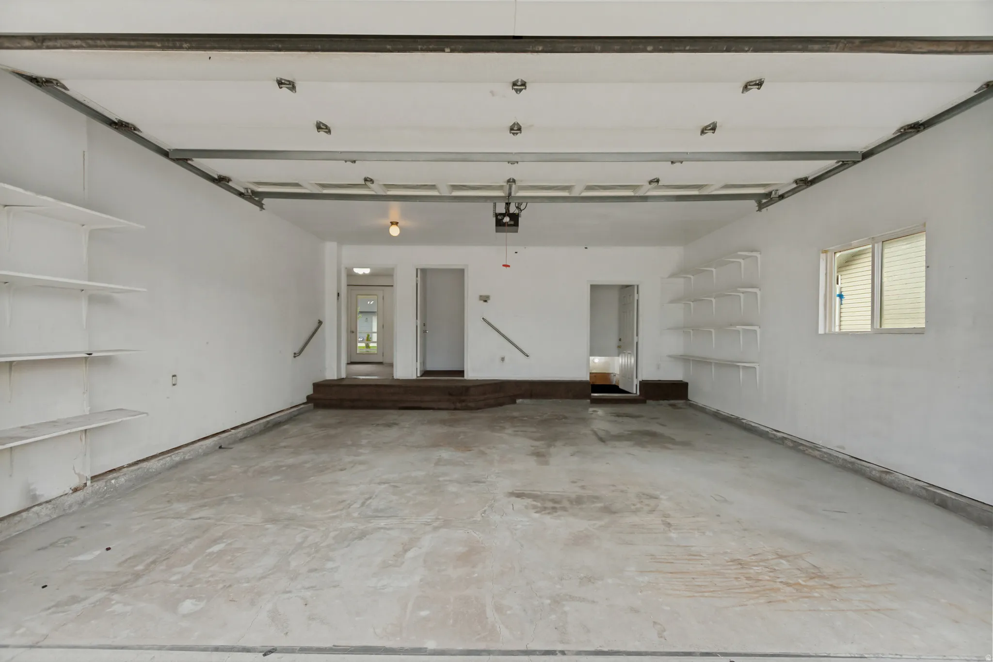 Spacious garage with a concrete floor, integrated shelving, and multiple access points