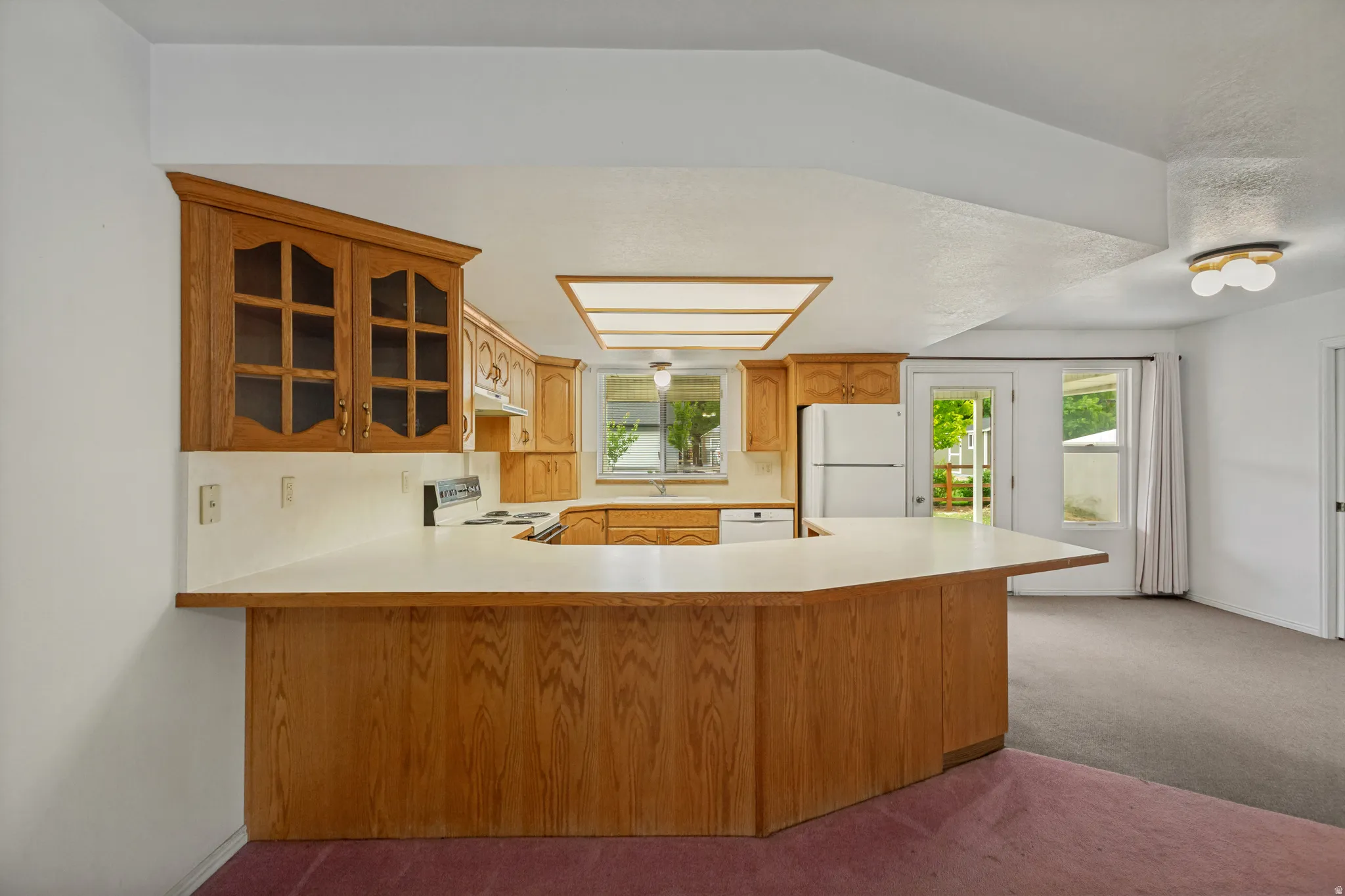 Wood-finish cabinetry with glass-front uppers, a U-shaped counter, and a built-in range
