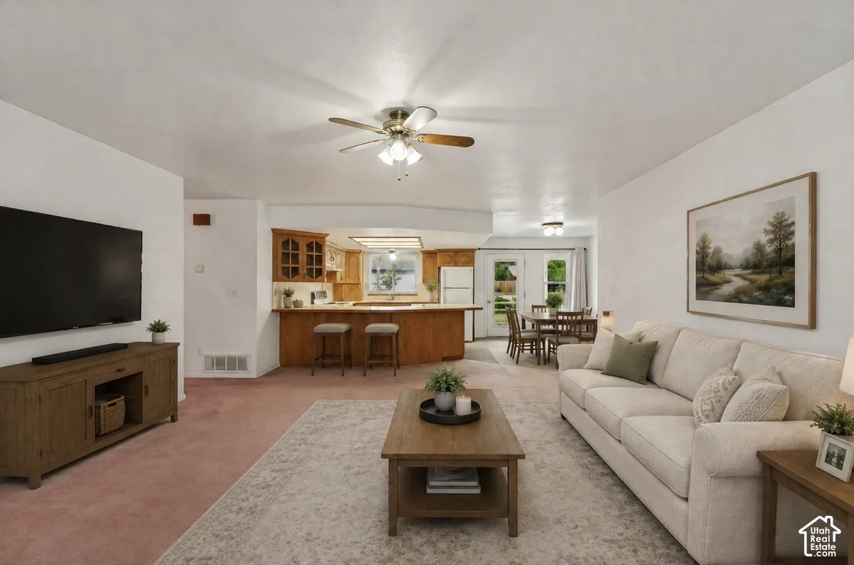 Open concept living area with ceiling fan and wood-finish cabinetry