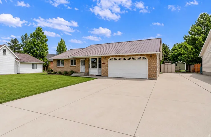Brick exterior with a metal roof, attached garage, and a concrete driveway/RV parking.