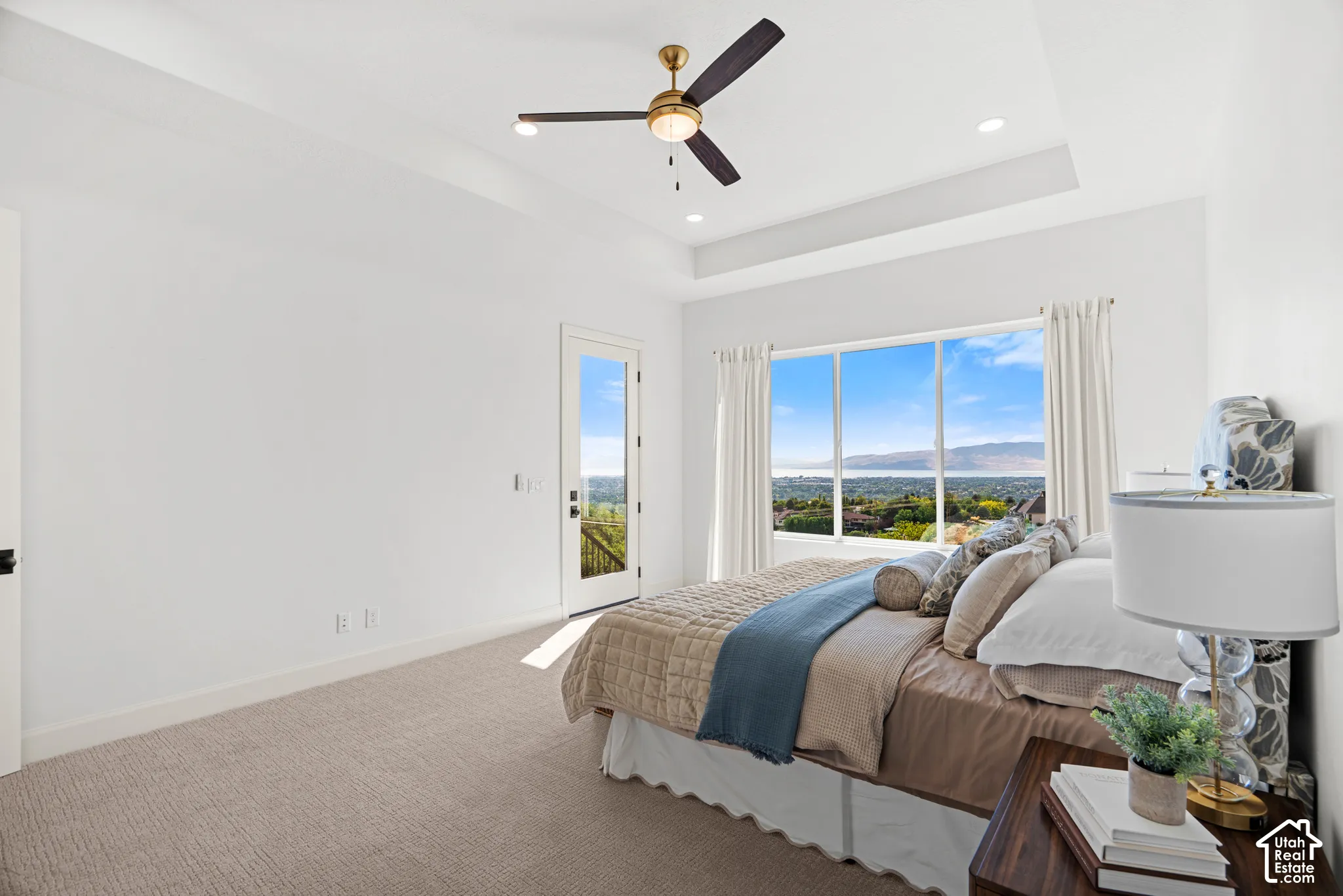 Recessed lighting, ceiling fan, tray ceiling, large picture window, and glass-paneled door