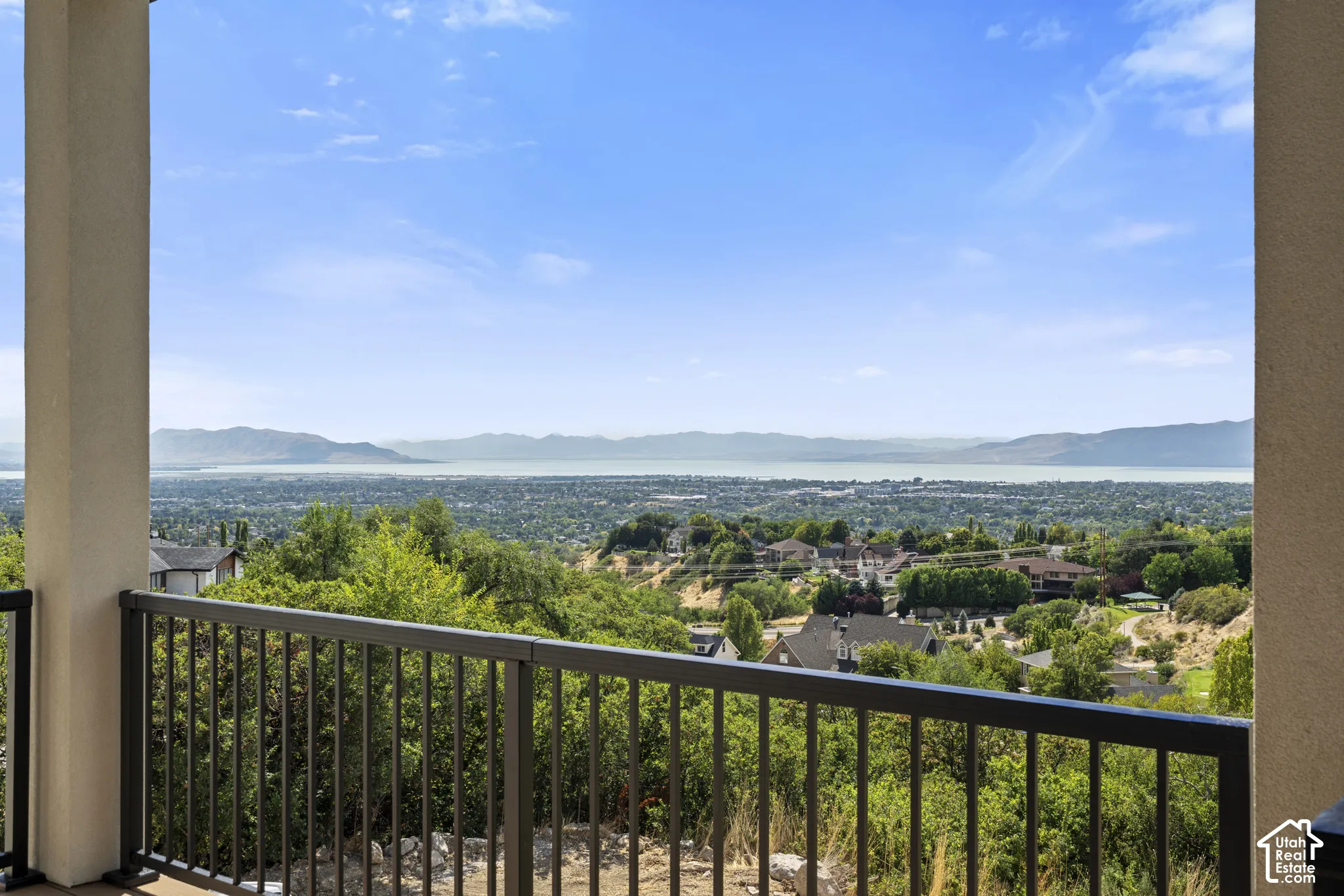 Balcony featuring a metal railing with a wide landscape and water backdrop
