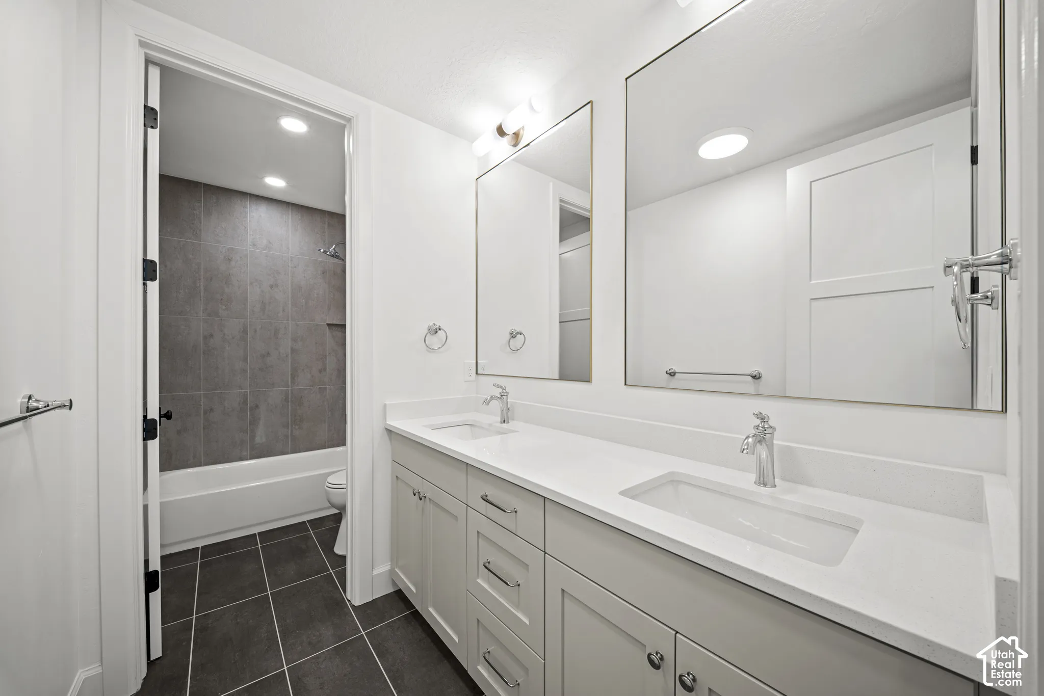 Double vanity with integrated sinks and chrome fixtures, framed mirrors, and light cabinetry