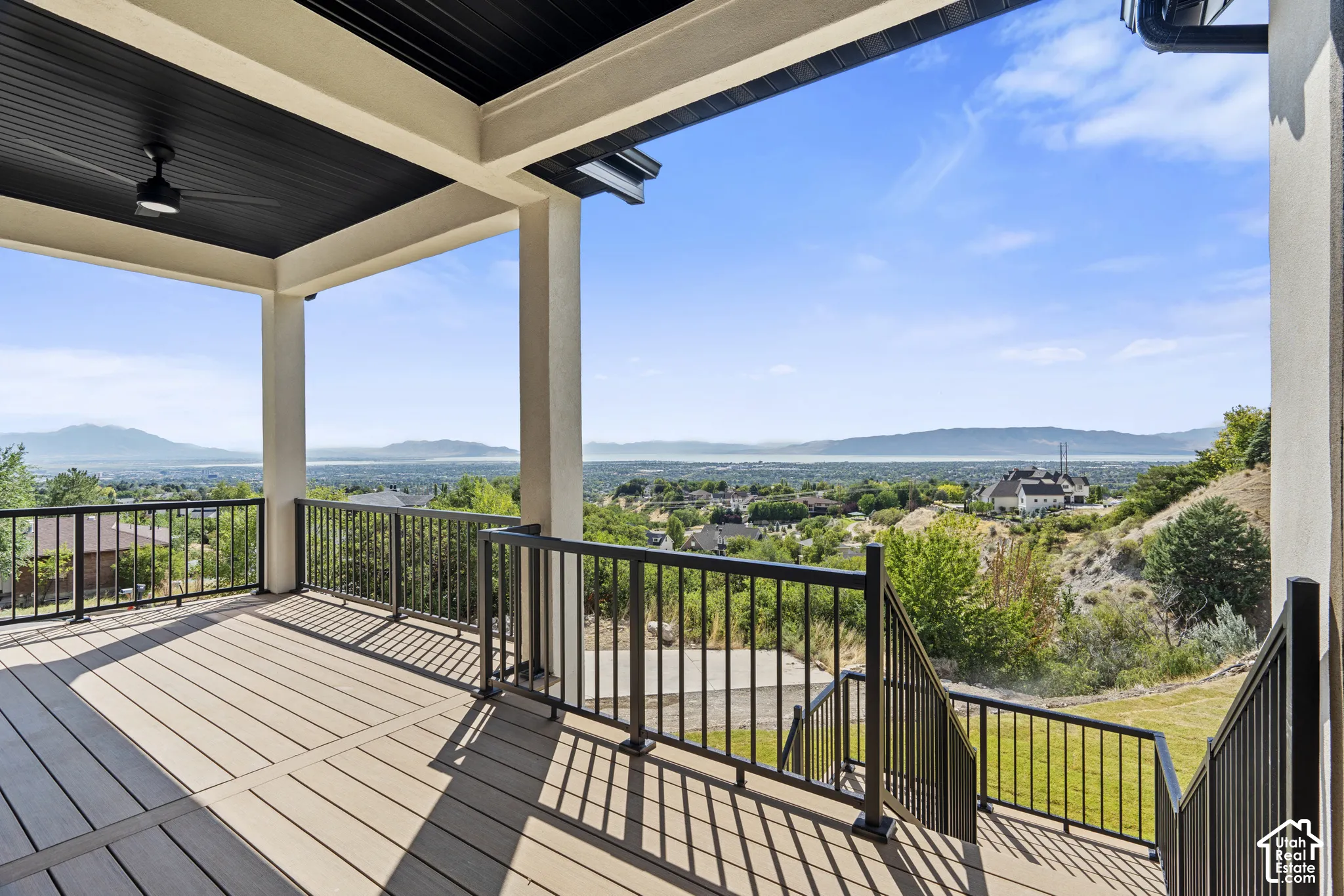 Covered outdoor deck with composite decking, black metal railings, and a ceiling fan