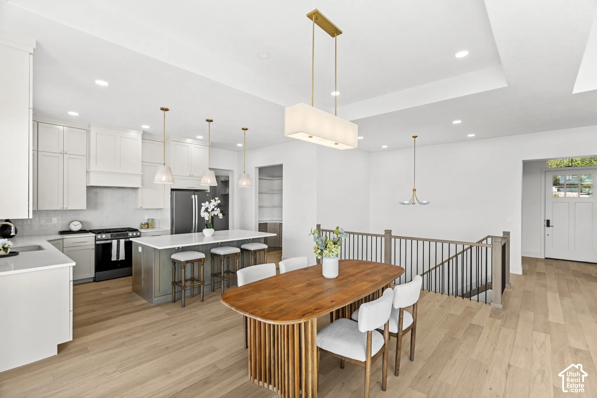 Kitchen featuring white shaker cabinetry, stainless steel appliances, a center island with pendant lighting, and wood-finish flooring