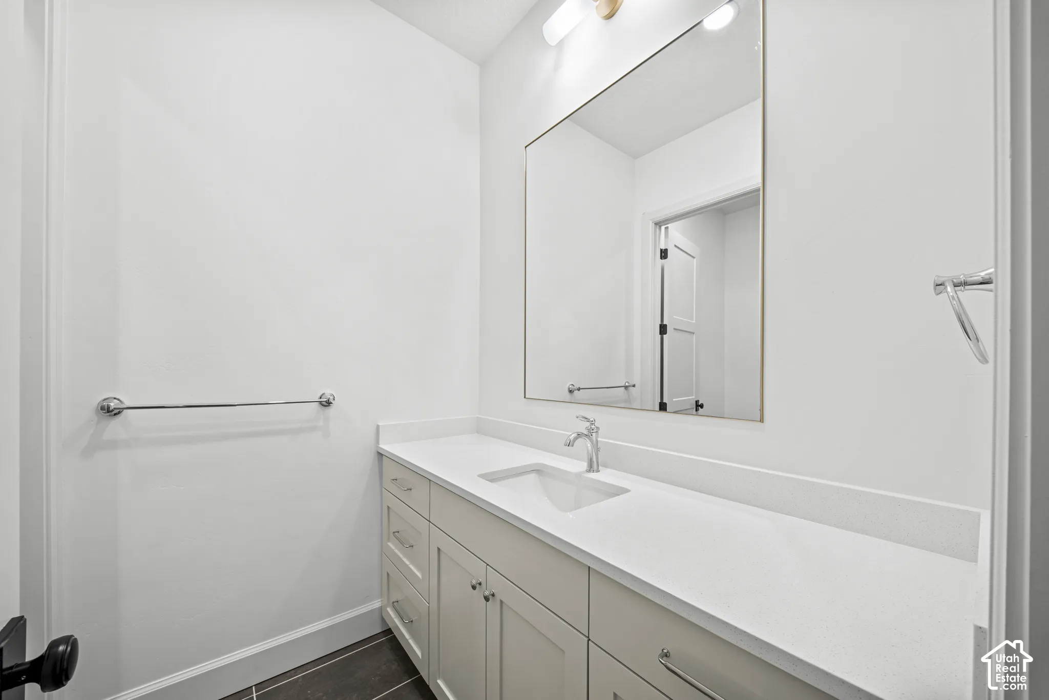 Recessed sink with chrome faucet, light-toned countertop, and recessed panel cabinetry