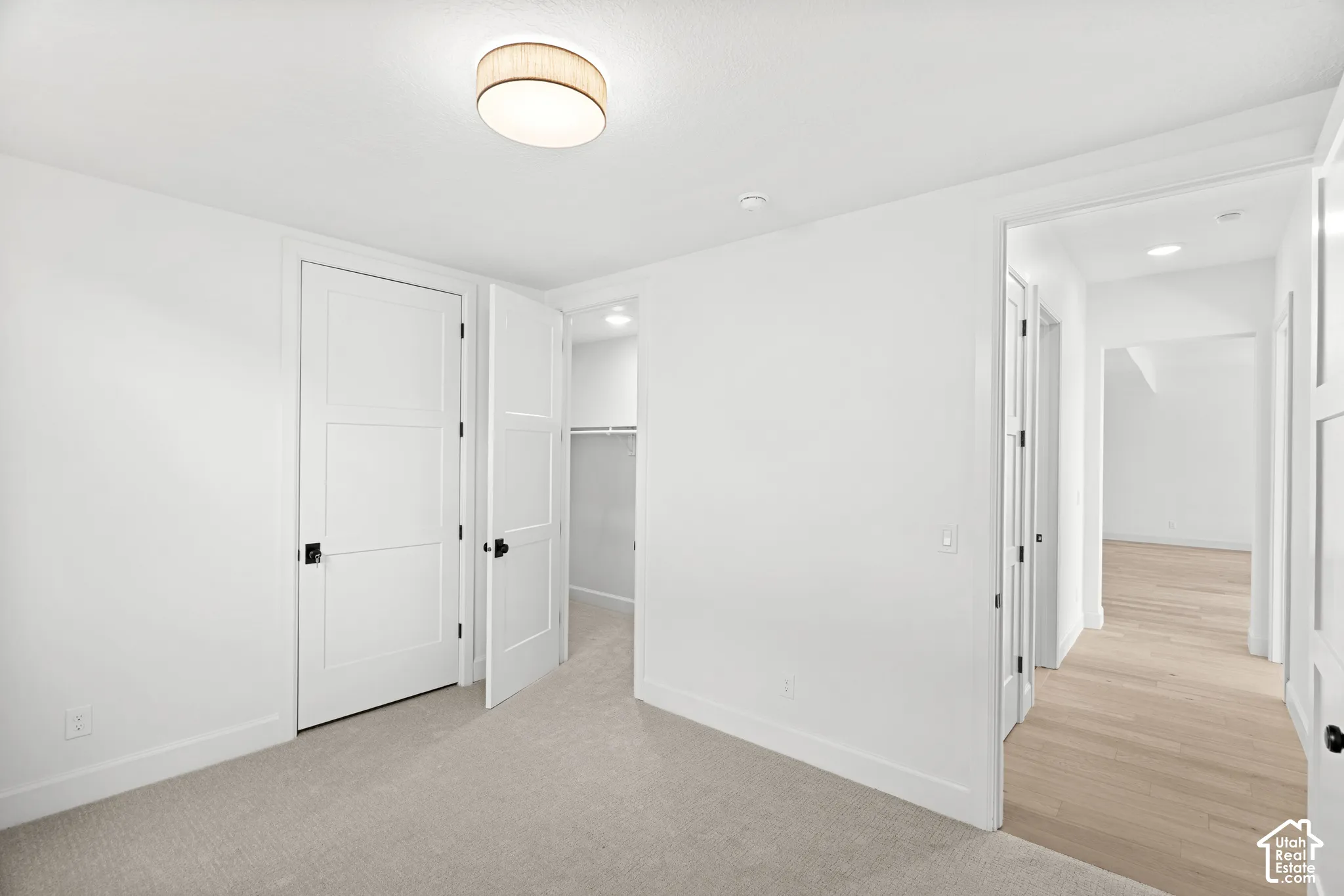 Carpeted room with a flush-mount ceiling light fixture, two panel doors with dark hardware, and an open closet