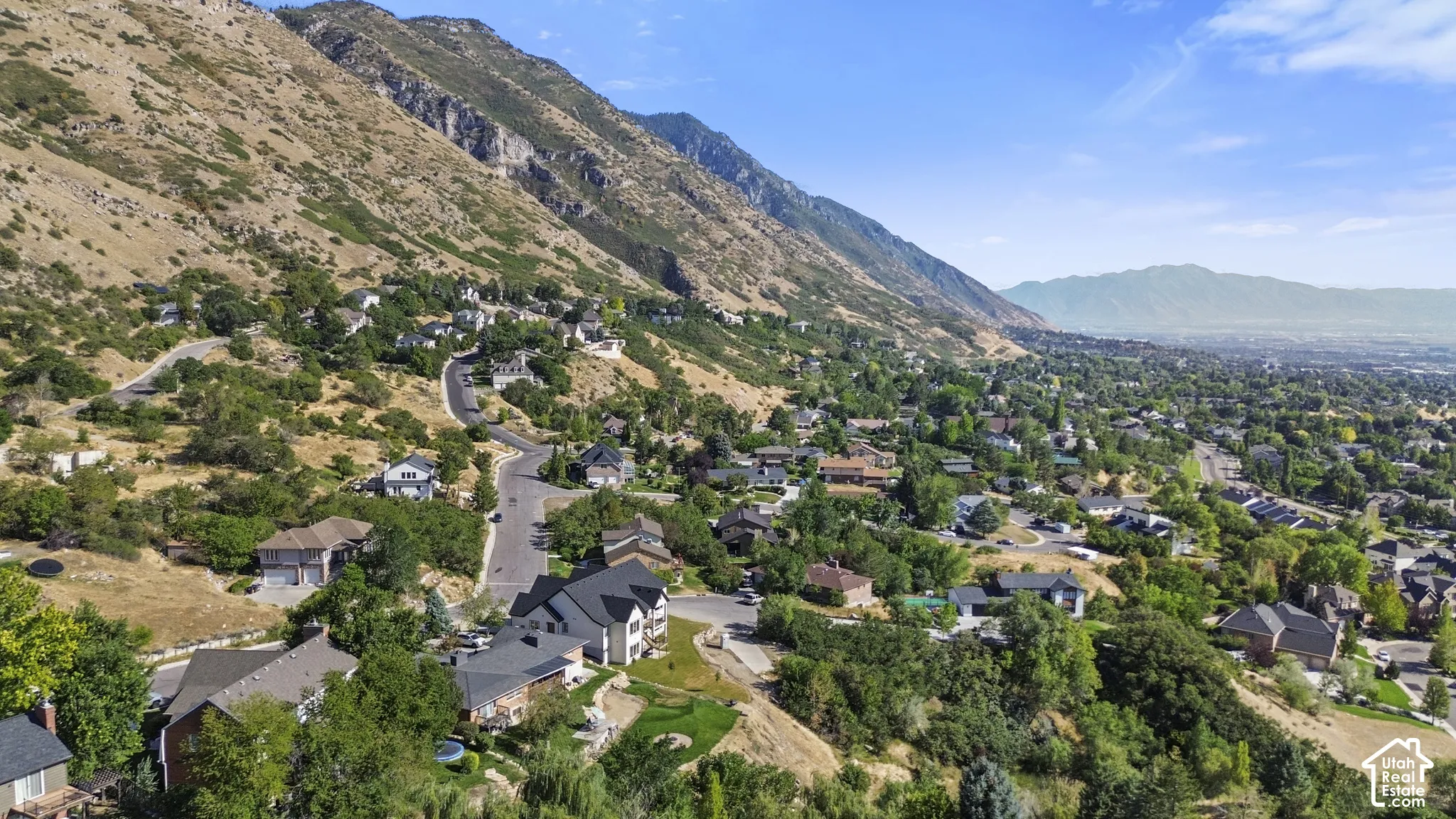 Mountainous terrain with residential properties, surrounded by natural landscaping and paved roadways