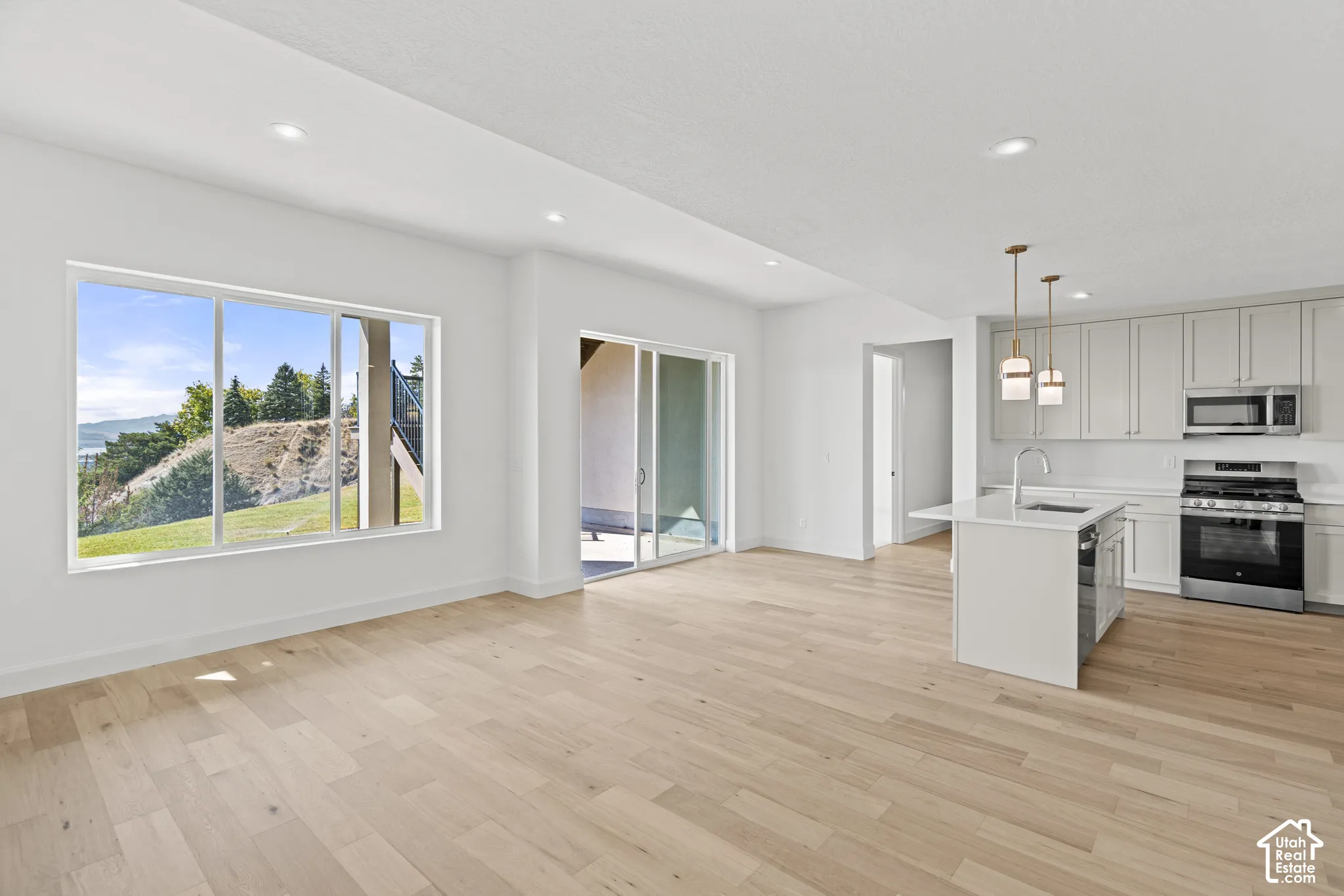 Open-concept living space featuring wood-finish flooring, recessed lighting, and a sliding glass door to an outdoor area