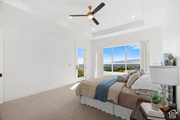 Recessed lighting, ceiling fan, tray ceiling, large picture window, and glass-paneled door