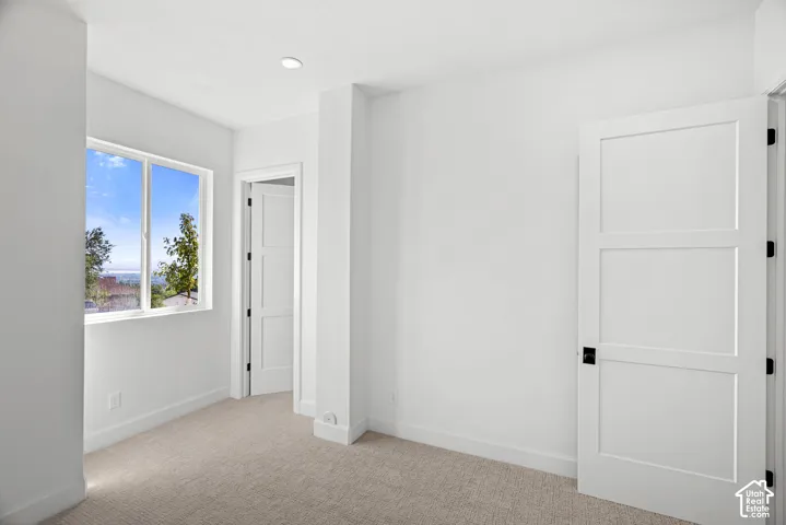 Bright interior with recessed lighting, light-toned carpeting, a multi-pane window, and a white three-panel door with matte black hardware