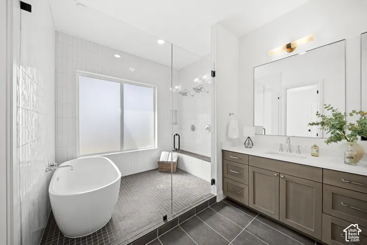 Freestanding soaking tub, glass-enclosed shower with integrated bench, dual vanity with undermount sink, quartz countertop, and large framed mirror