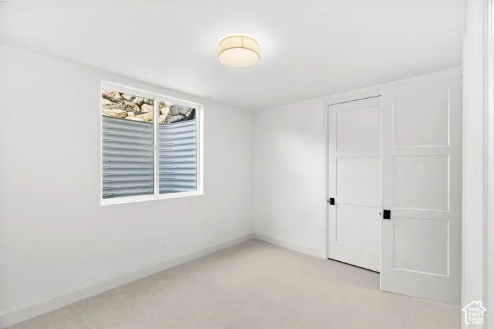 Window well, two-panel interior doors, low-pile carpeting, and a flush mount ceiling light fixture