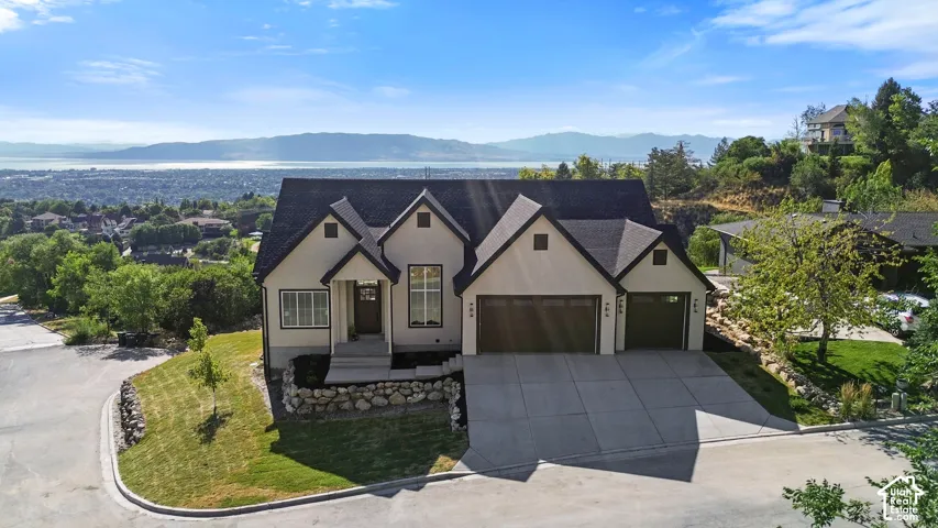 Contemporary stucco exterior with a multi-car concrete driveway, a prominent gabled roofline, and integrated two-car garage doors