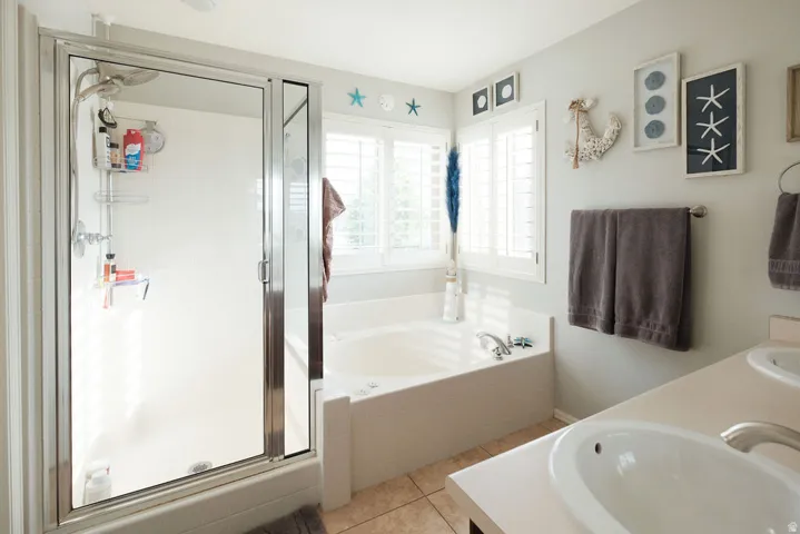 Walk-in shower with glass enclosure, separate soaking tub, and dual vanity sinks
