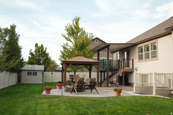 Expansive backyard featuring a manicured lawn, a large concrete patio, and a dedicated storage shed