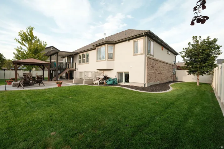 Expansive backyard with a manicured lawn, a concrete patio, and a covered pergola