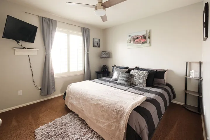 Ceiling fan, window with shutters, light gray walls, built-in wall shelf