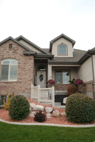 Brick and stucco exterior with an arched entry, a pitched roof, and a dormer window