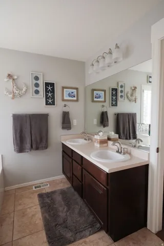 Dual vanity with integral sinks, dark wood-finish cabinetry, and neutral-toned countertop