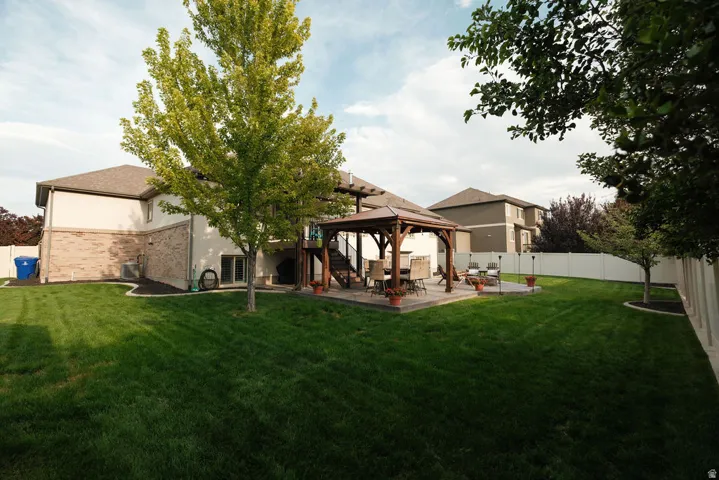Expansive backyard featuring a lush lawn, a patio with a gazebo, and mature trees