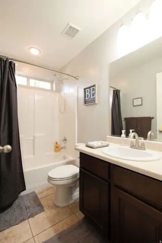 Bathroom featuring a white tub/shower combination, dark wood-finish vanity with a light-colored countertop, and a single basin sink