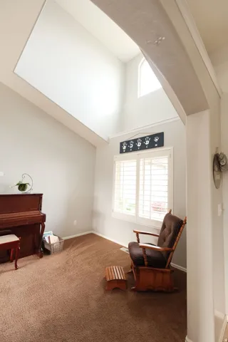 Arched entryway with a vaulted ceiling, upper wall window, and a large window with plantation shutters