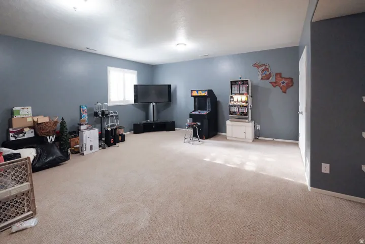 Spacious recreation room with neutral carpet flooring, recessed ceiling lighting, and large window providing natural illumination