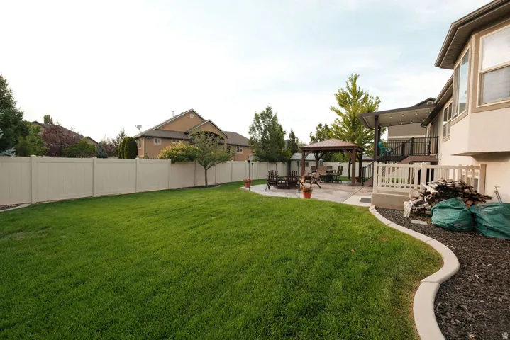 Expansive backyard featuring a manicured lawn, concrete patio, and a covered gazebo