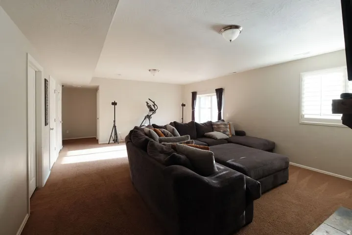 Recessed ceiling with flush mount lighting, two windows with white plantation shutters, and textured neutral carpeting